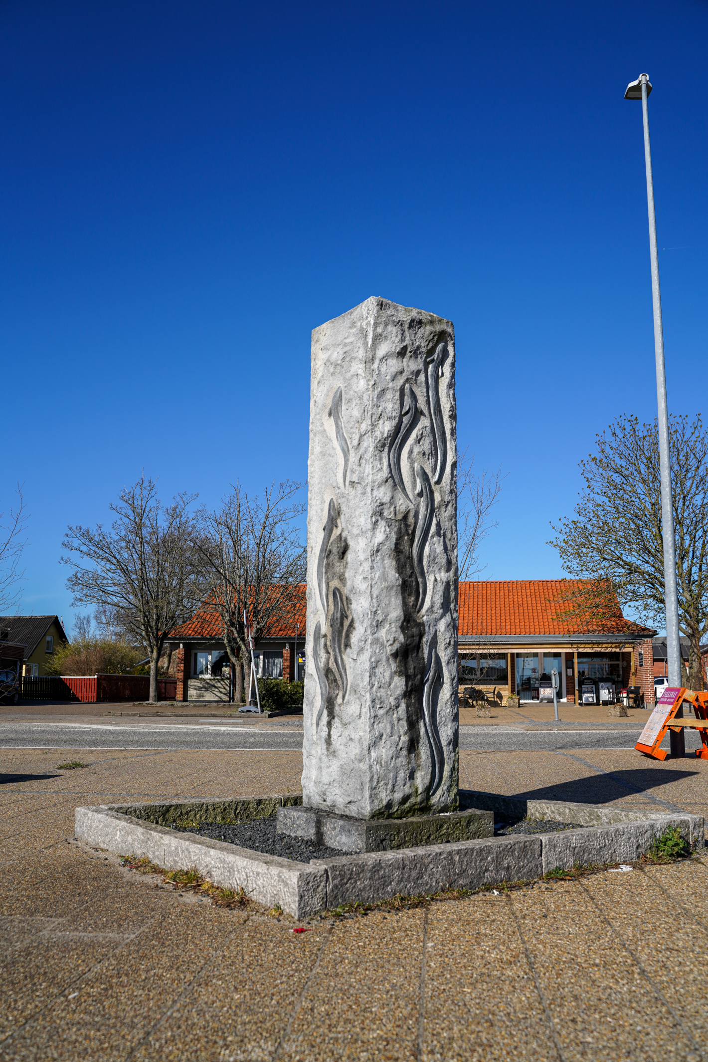 Høj firkantet granitsøjle med ål på siden