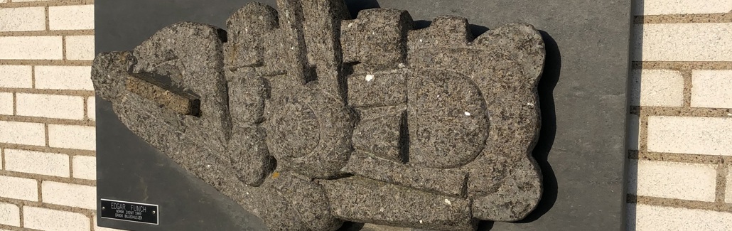 Stenrelief hængende på murstensmur