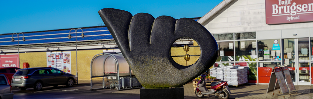 Mørk vingeformet granitskulptur med hul i