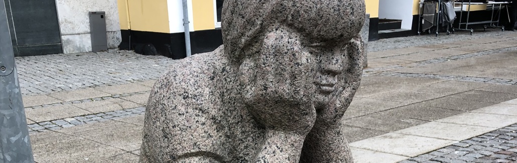 Dreng der sidder og støtter hovedet med sine hænder