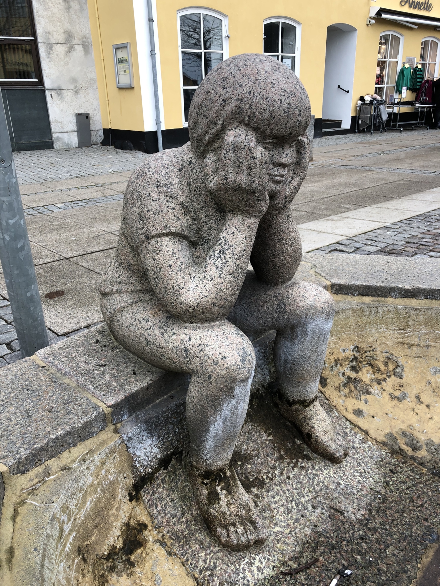 Dreng der sidder og støtter hovedet med sine hænder
