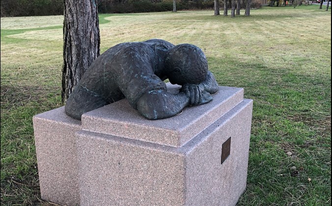 Skulptur af mand, der hviler sig på en granitklods