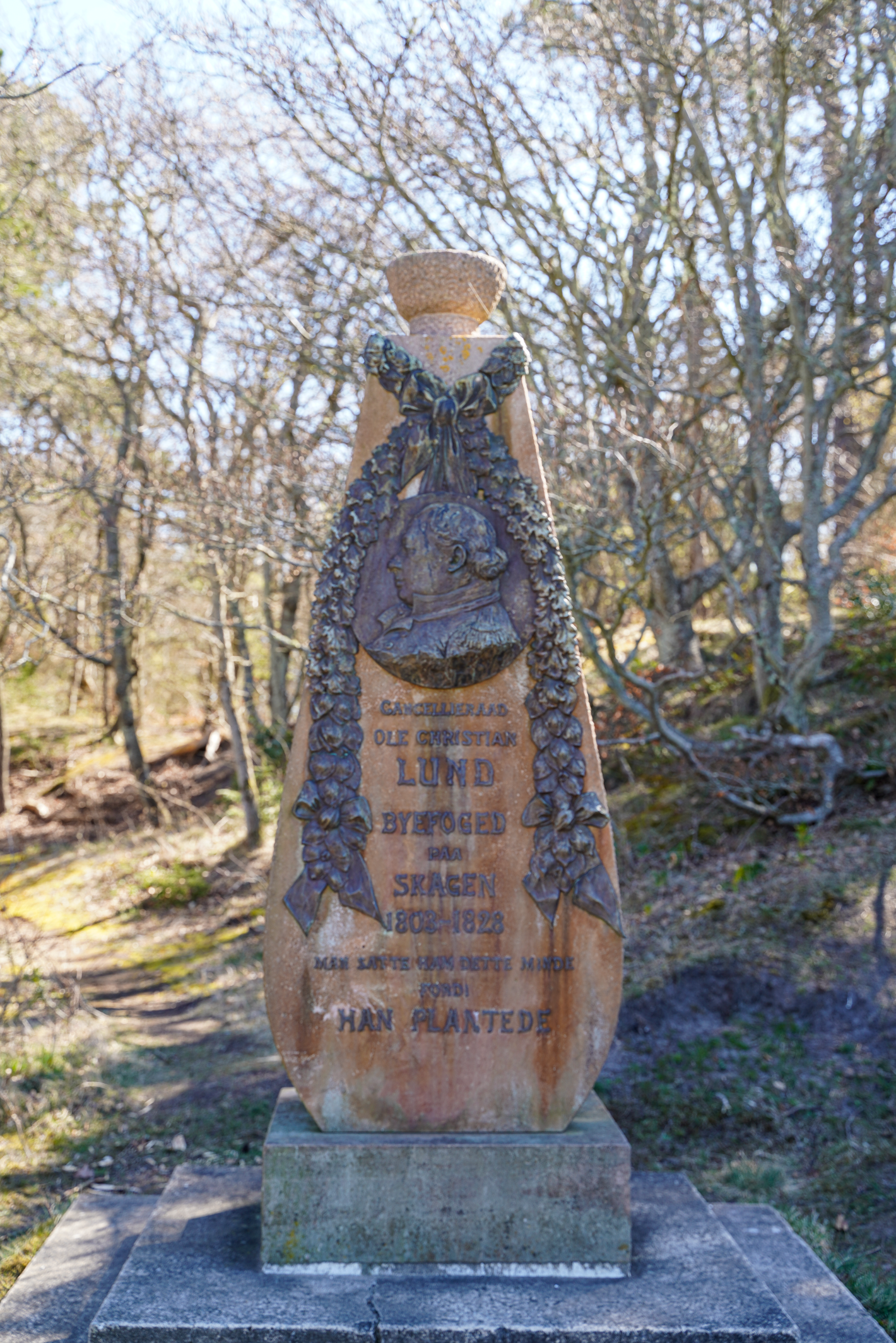 Høj rødlig mindesten med bronzeudsmykning