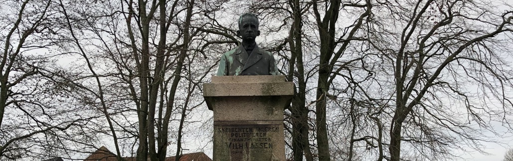 Buste af mand på høj granitsokkel med kvinde i kjole