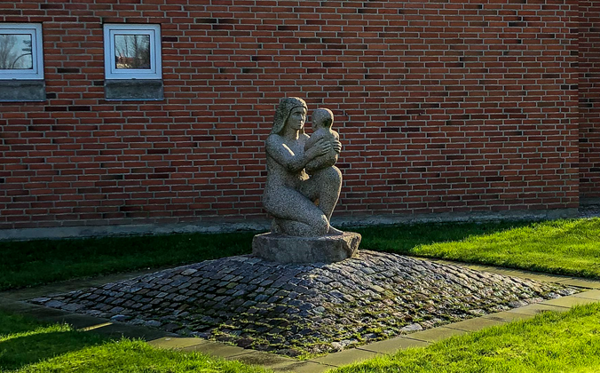 Granitskulptur af mor med sit barn på knæet
