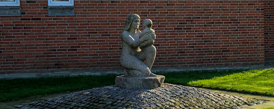Granitskulptur af mor med sit barn på knæet