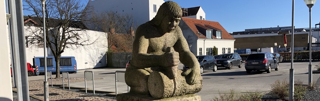 Granitskulptur af mand der udhugger hjul