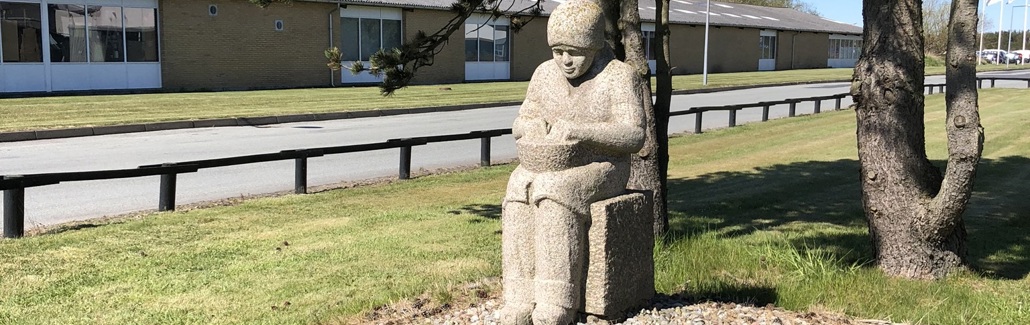 Siddende pige af granit med skål i skødet