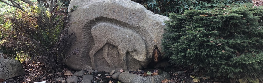 Stenskulptur af dyr der drikker ved en kilde