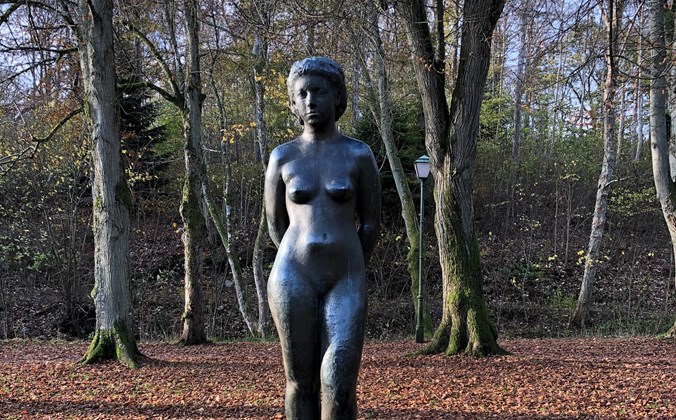 Bronzeskulptur af nøgen kvinde med hænderne på ryggen