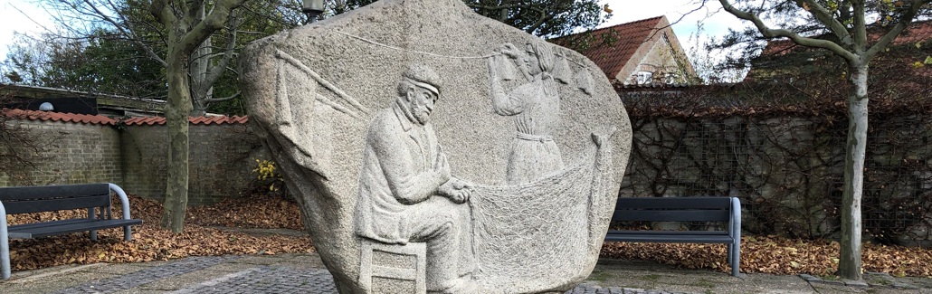 Stor sten med fisker der sidder ved sit garn