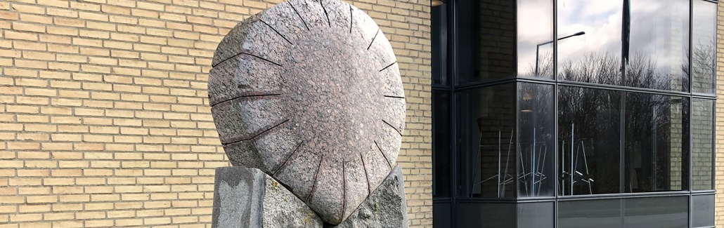 Granitskulptur med en sol liggende på to søjler