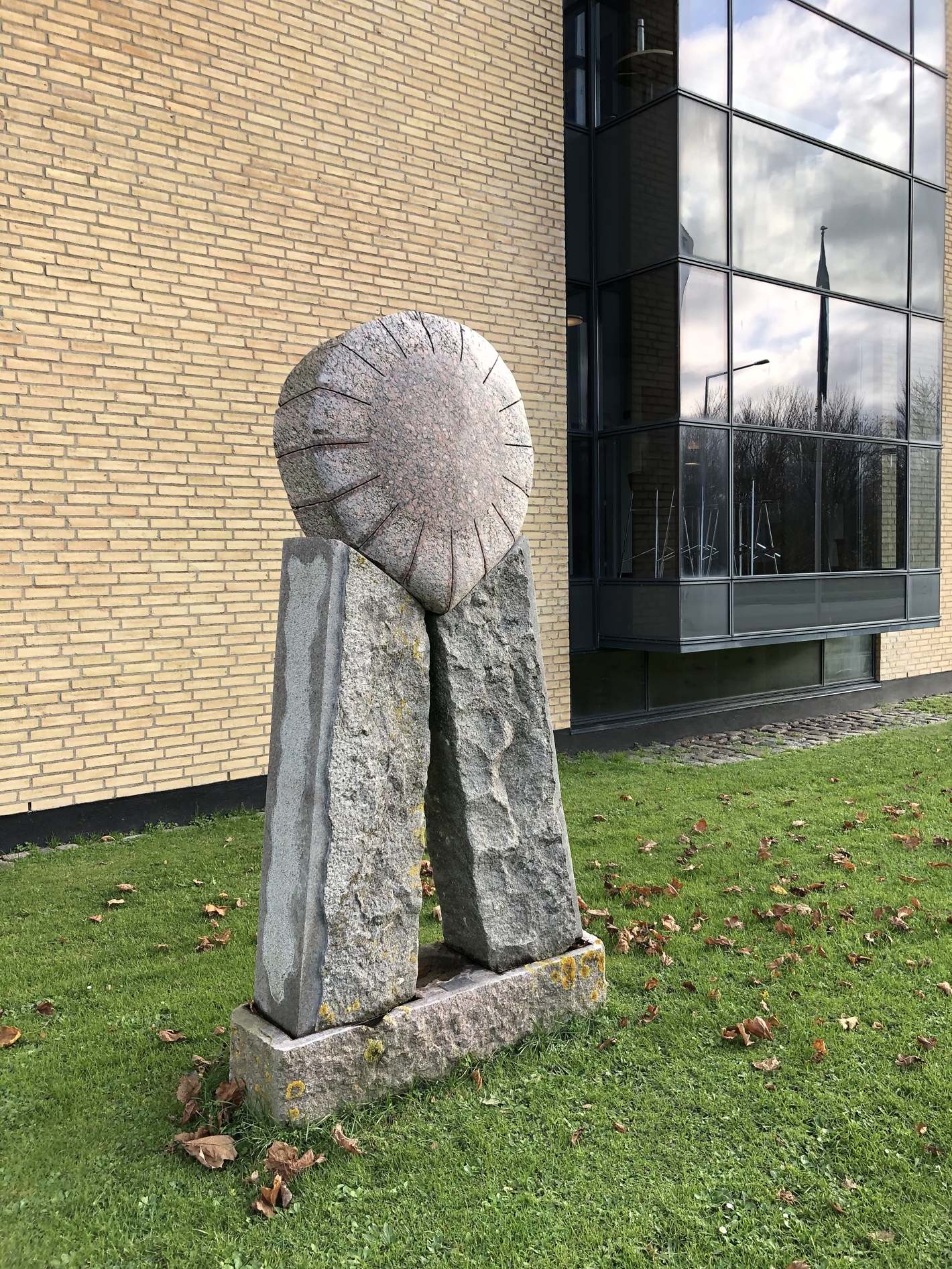 Granitskulptur med en sol liggende på to søjler