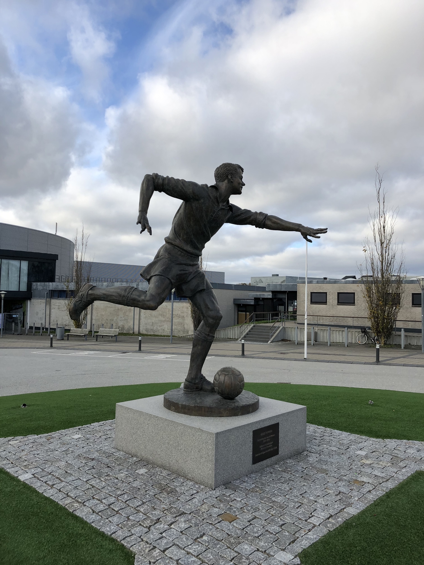 Bronzeskulptur af fodboldspiller på firkantet granitsokkel