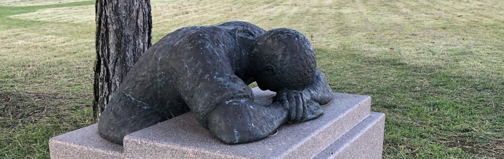 Skulptur af mand, der hviler sig på en granitklods