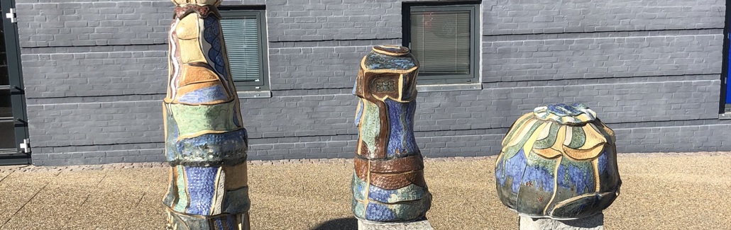 Tre farverige figurer på granitsøjler