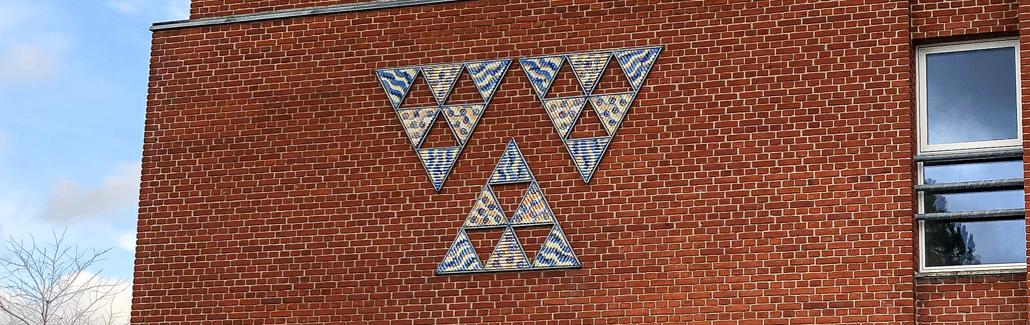 Keramiktrekanter der hænger på murstensvæg