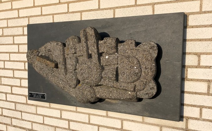 Stenrelief hængende på murstensmur