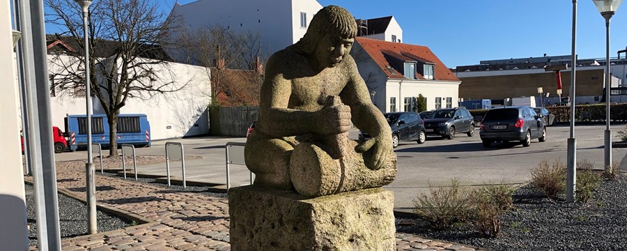 Granitskulptur af mand der udhugger hjul
