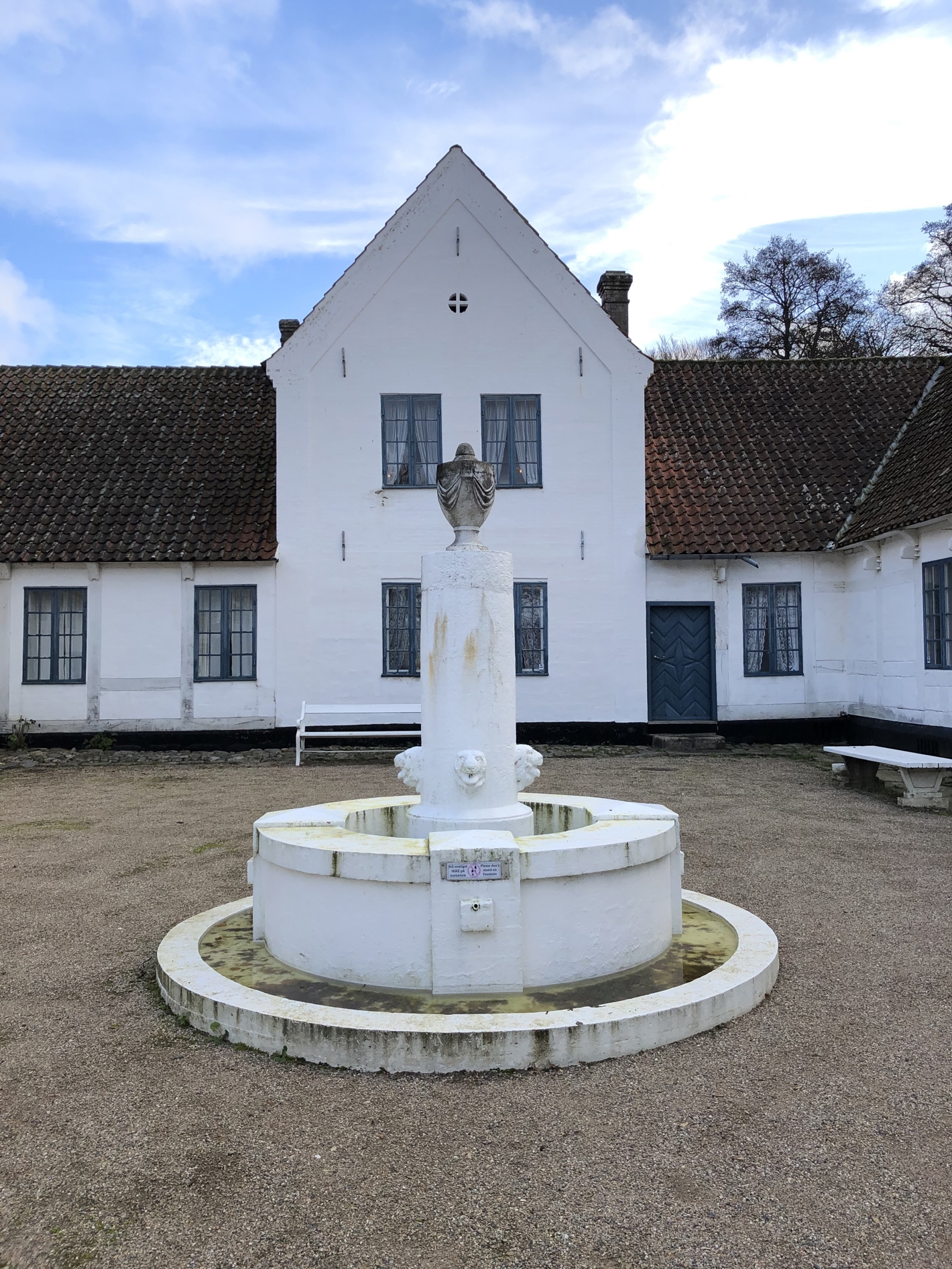 Hvid brønd med søjle med løver i midten