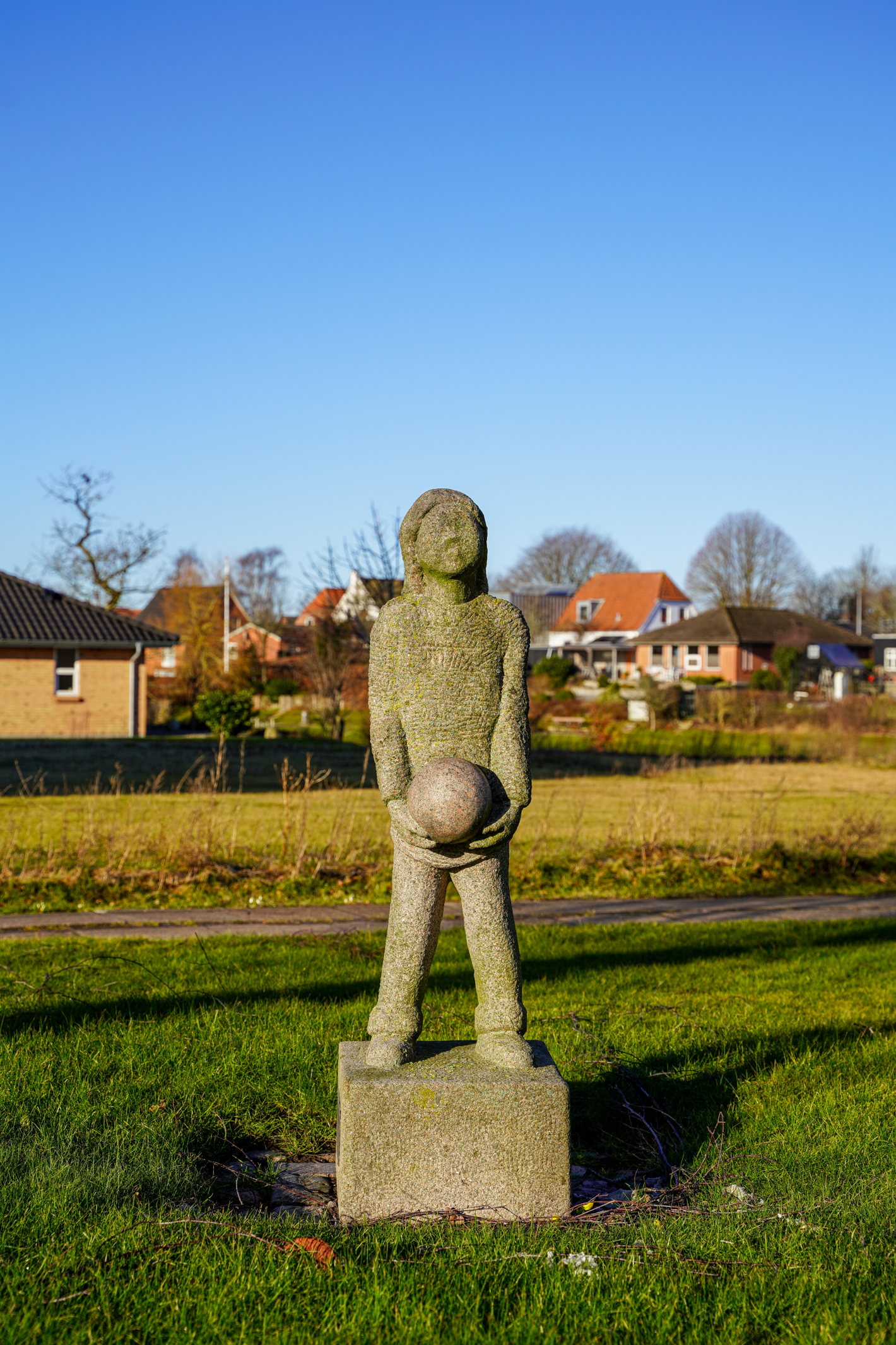 Pige med bold i hænderne i granit