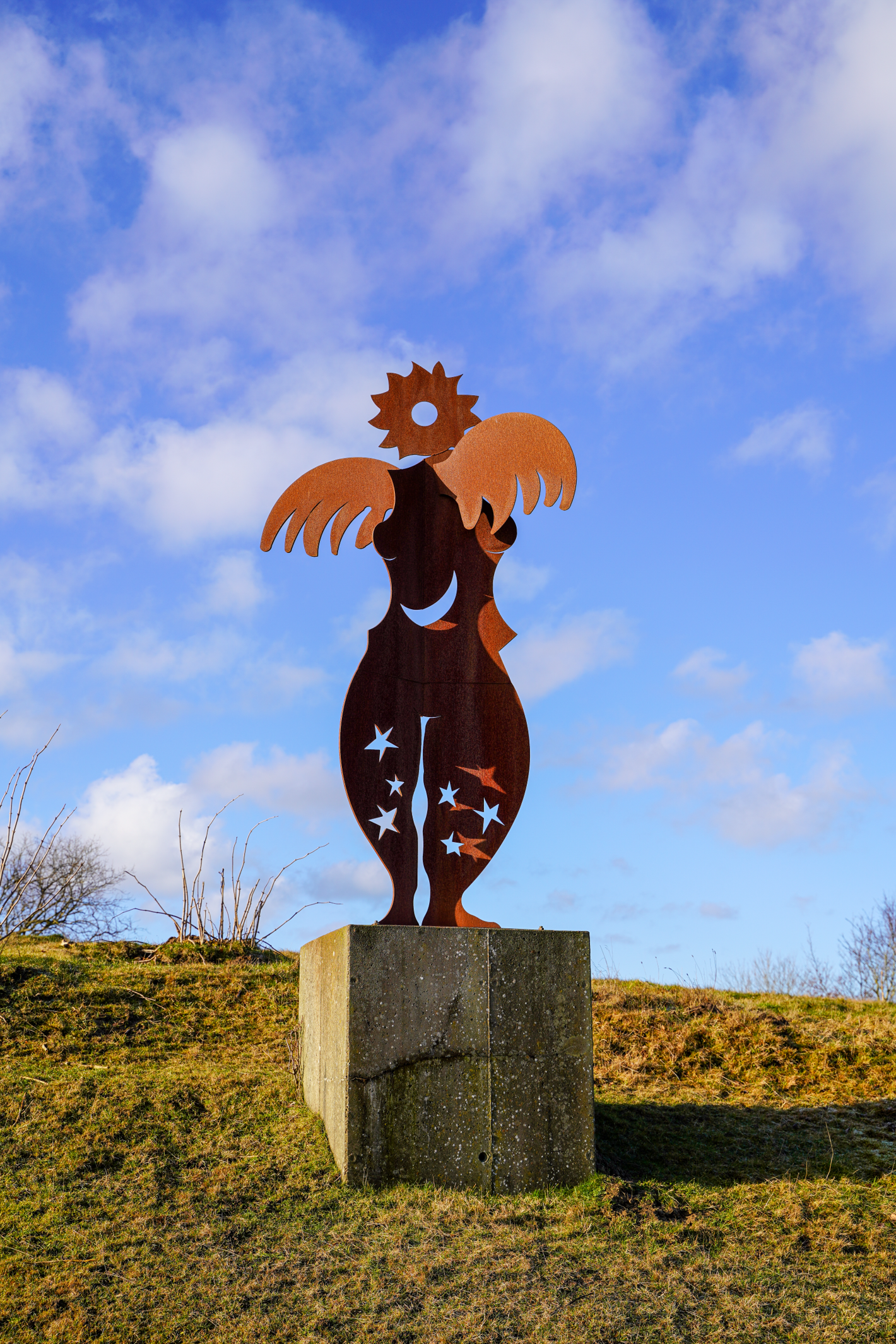 Rustfarvet metalengel på firkantet sokkel