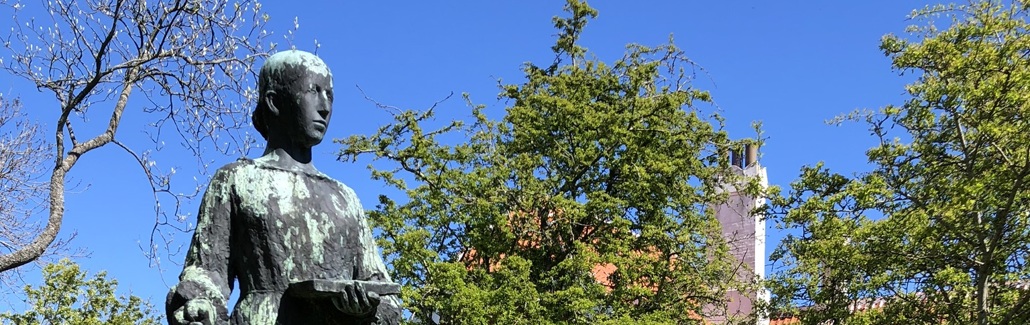 Statue af kvinde i kjole på høj sokkel