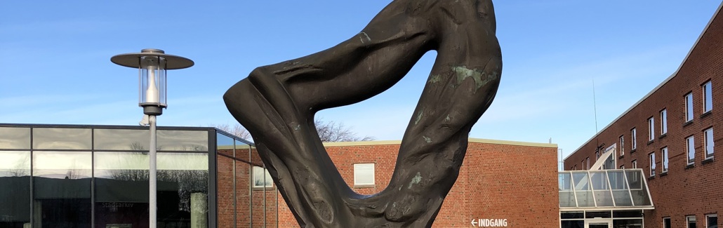 Trekantet skulptur med organiske former på sokkel