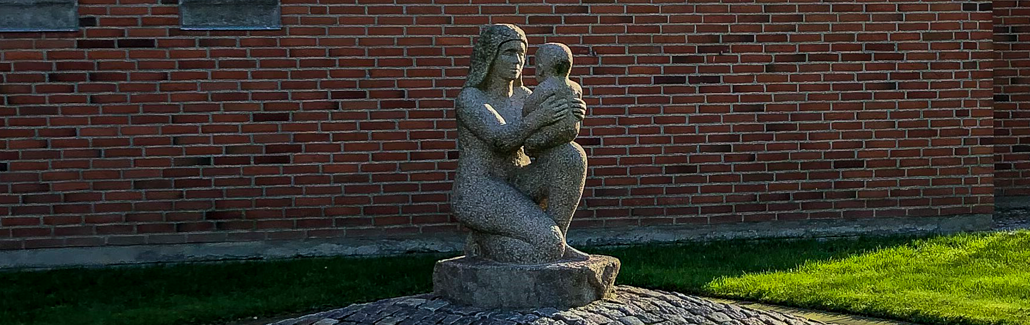 Granitskulptur af mor med sit barn på knæet