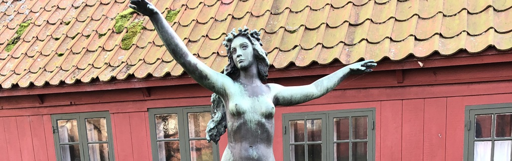 Bronzestatue af havfrue stående på høj sokkel