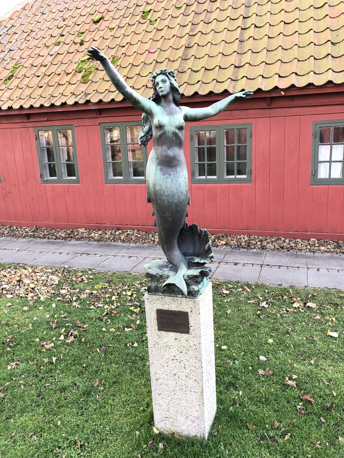 Bronzestatue af havfrue stående på høj sokkel