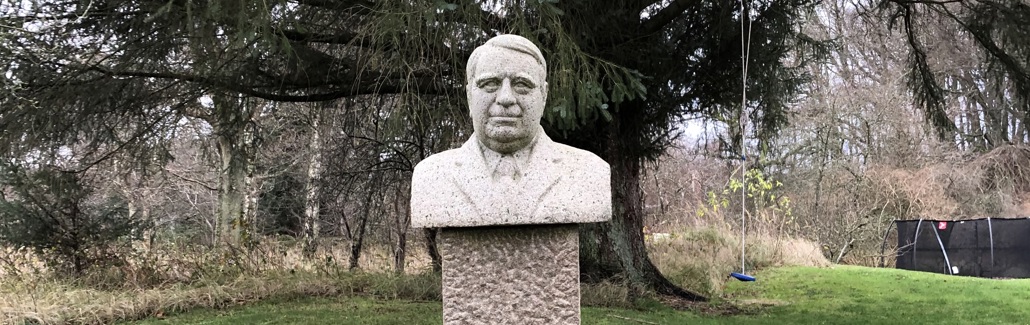 Granitbuste af mand med redt hår, skjorte, slips og jakke