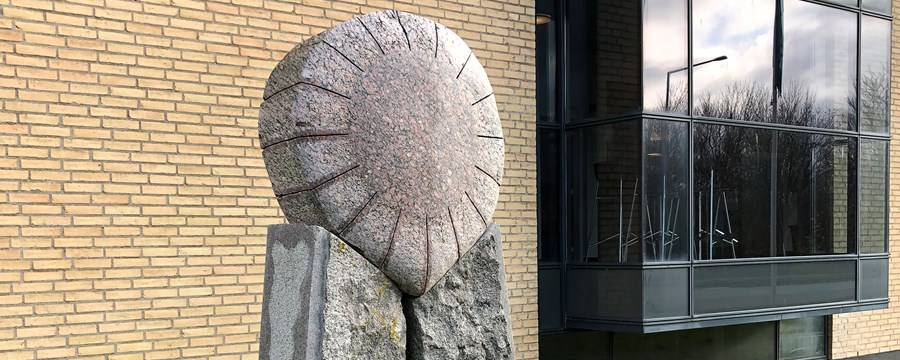Granitskulptur med en sol liggende på to søjler