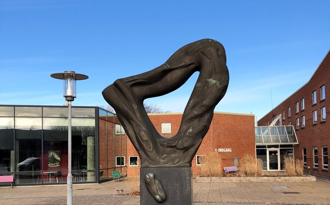 Trekantet skulptur med organiske former på sokkel